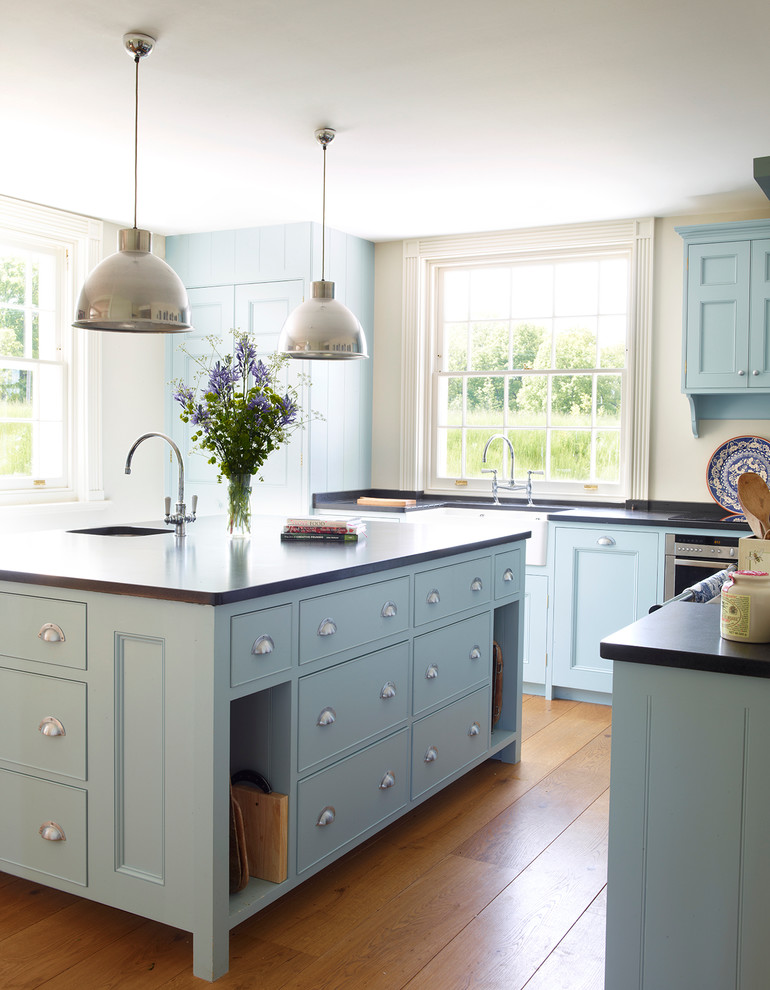 This is an example of a traditional l-shaped kitchen in Other with a farmhouse sink, recessed-panel cabinets, blue cabinets, medium hardwood floors and with island.