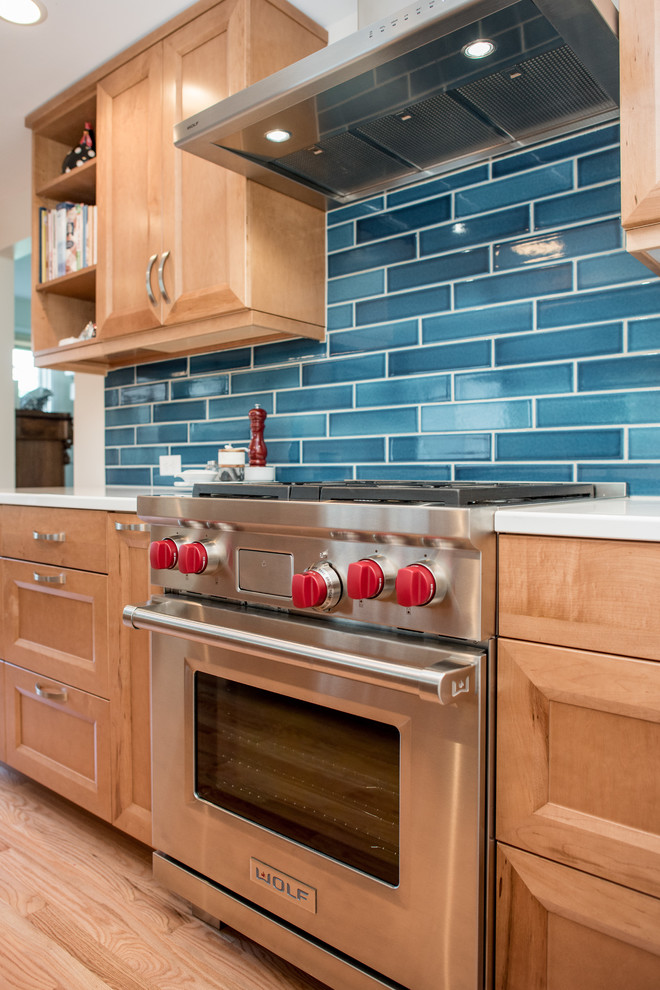 Photo of a transitional galley kitchen in Seattle with recessed-panel cabinets, light wood cabinets, quartz benchtops, blue splashback, porcelain splashback, stainless steel appliances, light hardwood floors, no island, beige floor and white benchtop.
