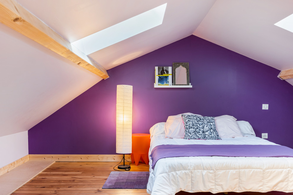 Réalisation d'une chambre mansardée ou avec mezzanine design de taille moyenne avec un mur violet, parquet clair et poutres apparentes.