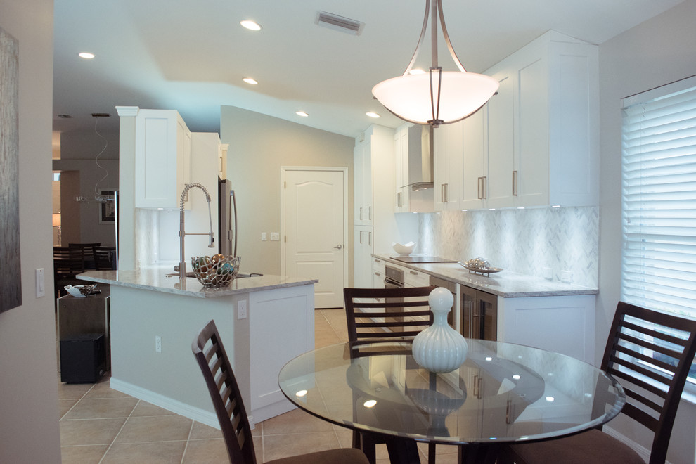 Inspiration for a mid-sized transitional galley ceramic tile and beige floor eat-in kitchen remodel in Miami with an undermount sink, shaker cabinets, white cabinets, granite countertops, gray backsplash, stone tile backsplash, stainless steel appliances and a peninsula