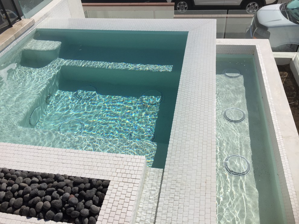 This is an example of a mid-sized contemporary front yard rectangular infinity pool in Los Angeles with a hot tub and concrete slab.