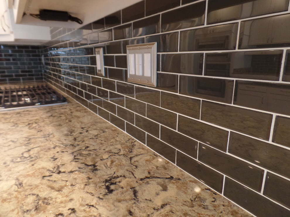 Large transitional u-shaped porcelain tile eat-in kitchen photo with an undermount sink, shaker cabinets, white cabinets, quartz countertops, green backsplash, glass tile backsplash, stainless steel appliances and a peninsula