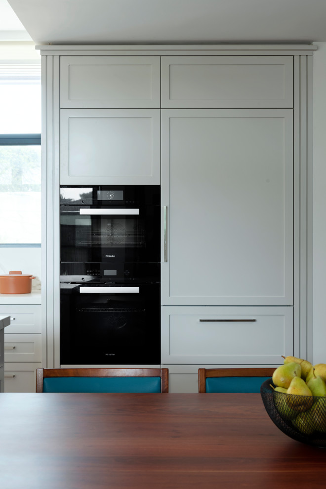 Design ideas for a large traditional l-shaped eat-in kitchen in Perth with an undermount sink, shaker cabinets, grey cabinets, solid surface benchtops, grey splashback, glass sheet splashback, black appliances, dark hardwood floors, with island, brown floor and multi-coloured benchtop.