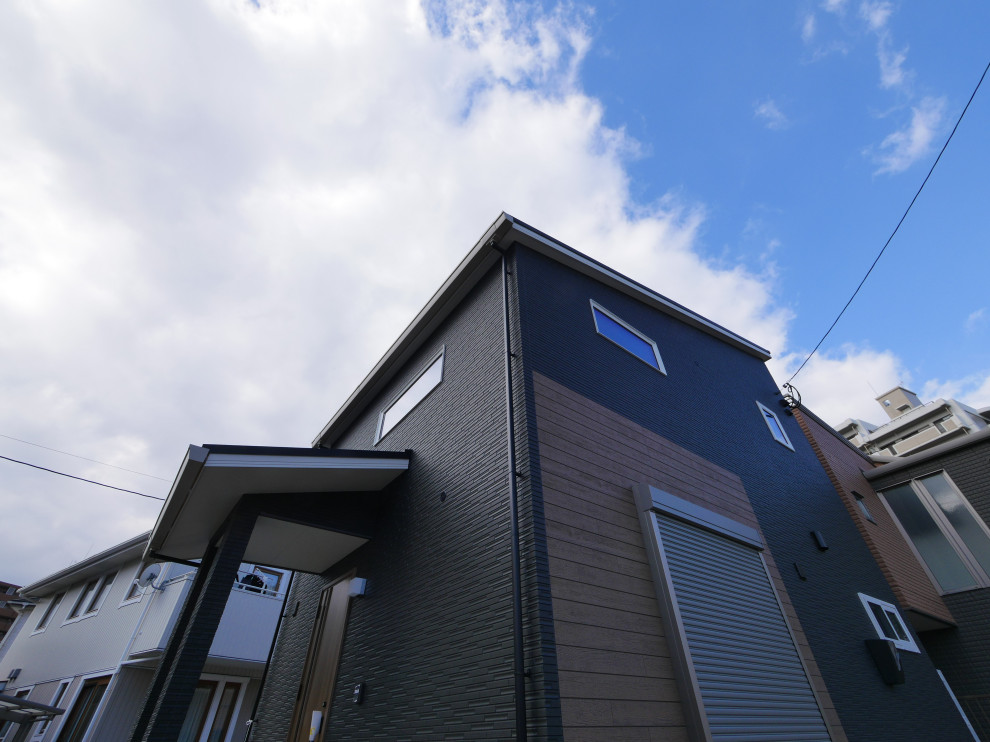 Cette image montre une petite façade de maison noire à un étage avec un revêtement mixte et un toit noir.