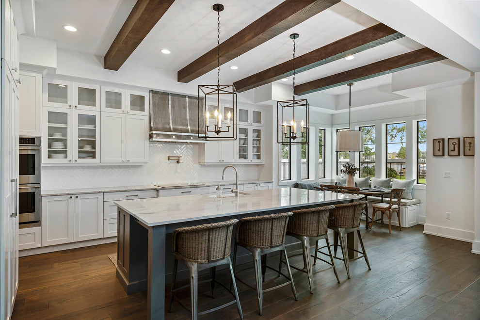 Inspiration for a large transitional l-shaped eat-in kitchen in Orlando with a farmhouse sink, glass-front cabinets, white cabinets, marble benchtops, white splashback, mosaic tile splashback, stainless steel appliances, medium hardwood floors, with island and white benchtop.