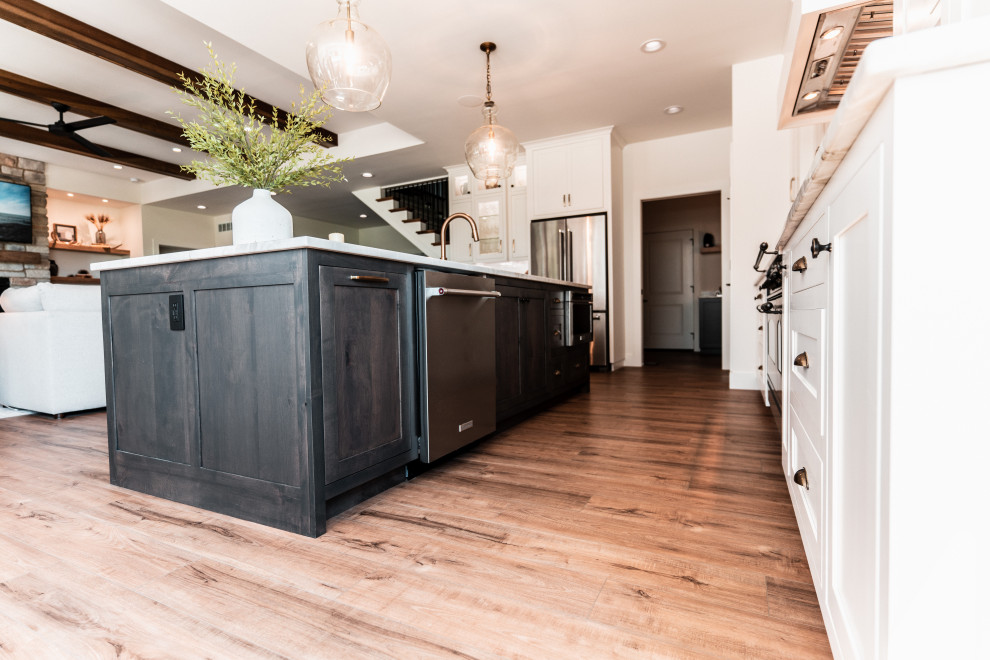 Open concept kitchen - large transitional l-shaped light wood floor open concept kitchen idea with an undermount sink, shaker cabinets, white cabinets, quartzite countertops, multicolored backsplash, porcelain backsplash, stainless steel appliances and an island