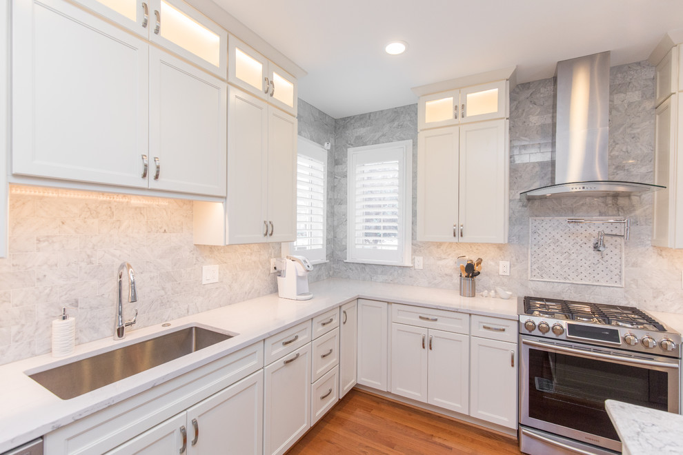 Mid-sized traditional l-shaped eat-in kitchen in DC Metro with an undermount sink, recessed-panel cabinets, white cabinets, marble benchtops, grey splashback, marble splashback, stainless steel appliances, medium hardwood floors, with island and brown floor.