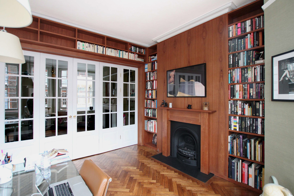 Photo of an expansive midcentury study room in London with green walls, medium hardwood floors, a standard fireplace and a freestanding desk.