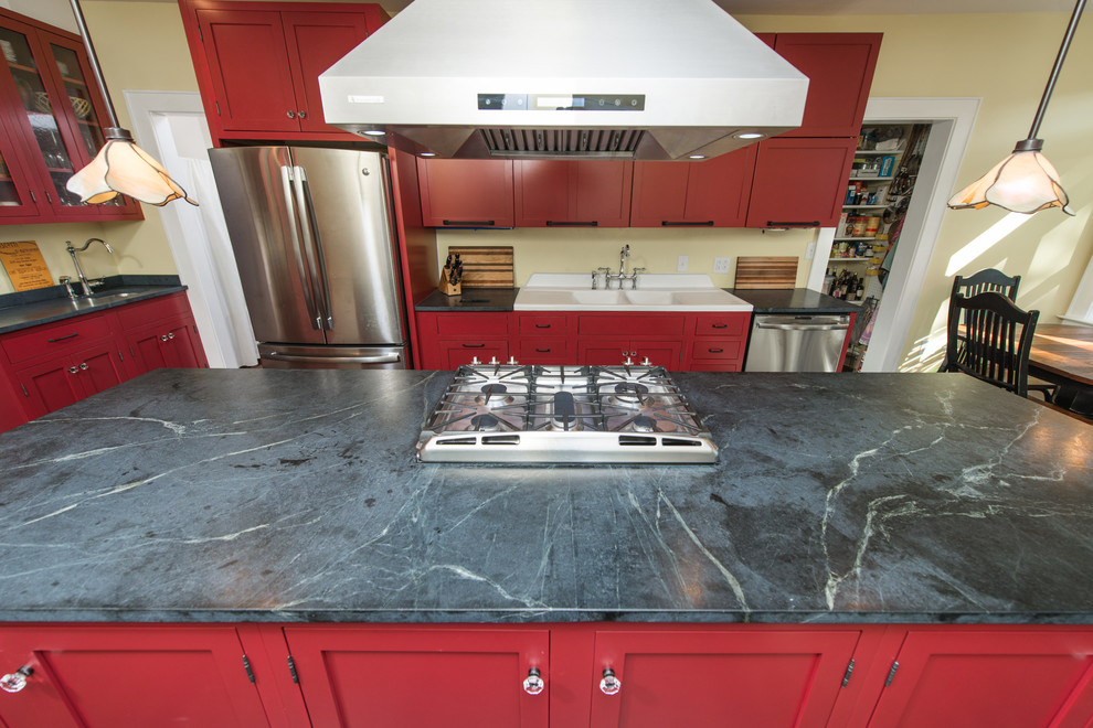 Example of a mid-sized trendy galley dark wood floor and brown floor eat-in kitchen design in Other with a double-bowl sink, raised-panel cabinets, red cabinets, soapstone countertops, stainless steel appliances and an island