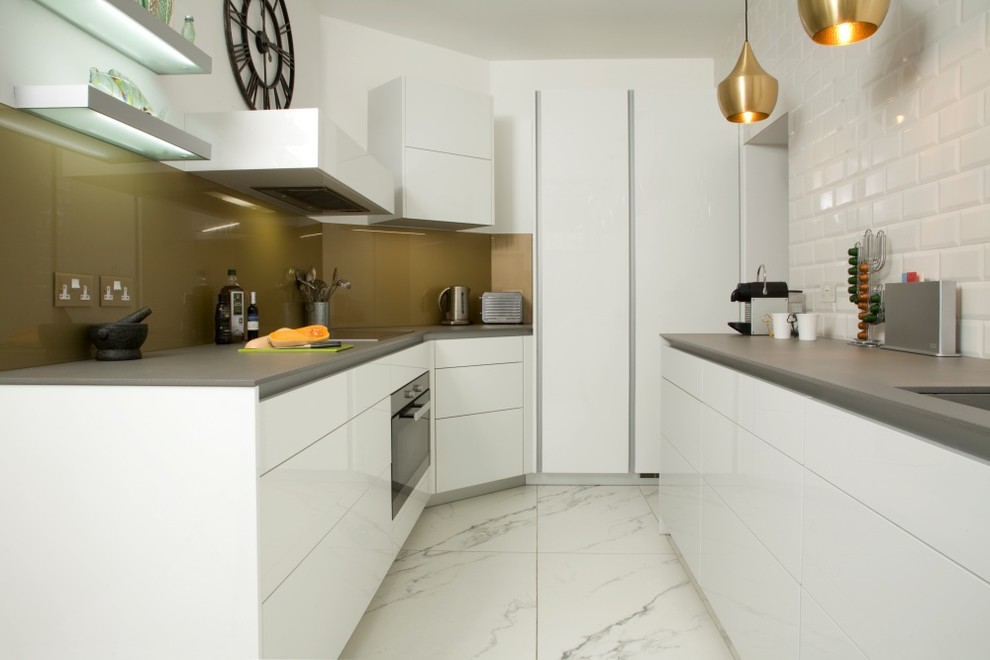 Design ideas for a small contemporary galley separate kitchen in London with an undermount sink, flat-panel cabinets, white cabinets, solid surface benchtops, metallic splashback, glass sheet splashback, stainless steel appliances, marble floors, white floor, grey benchtop and no island.