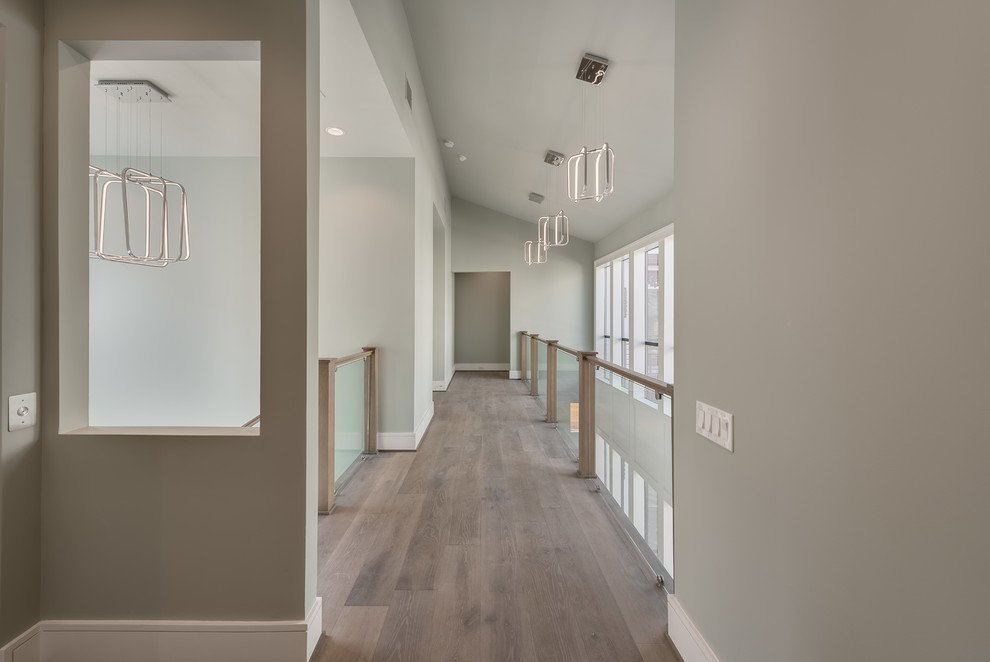 Hallway - large modern light wood floor hallway idea in Houston with gray walls