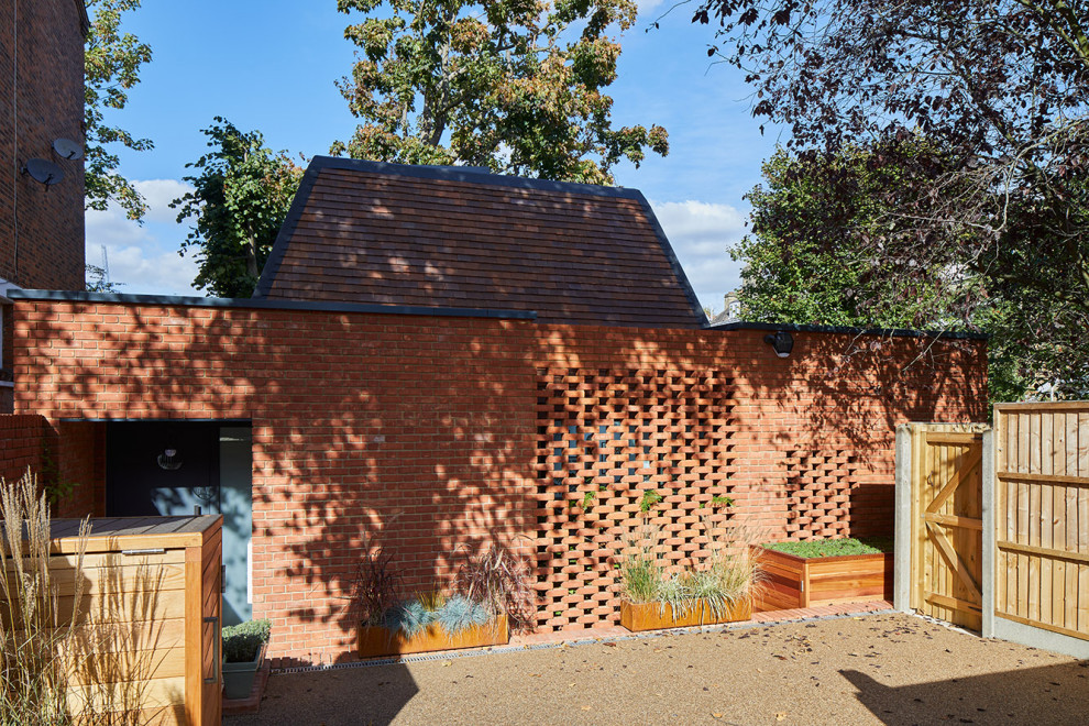 Modelo de fachada de casa roja contemporánea de tamaño medio de dos plantas con revestimiento de ladrillo y tejado plano
