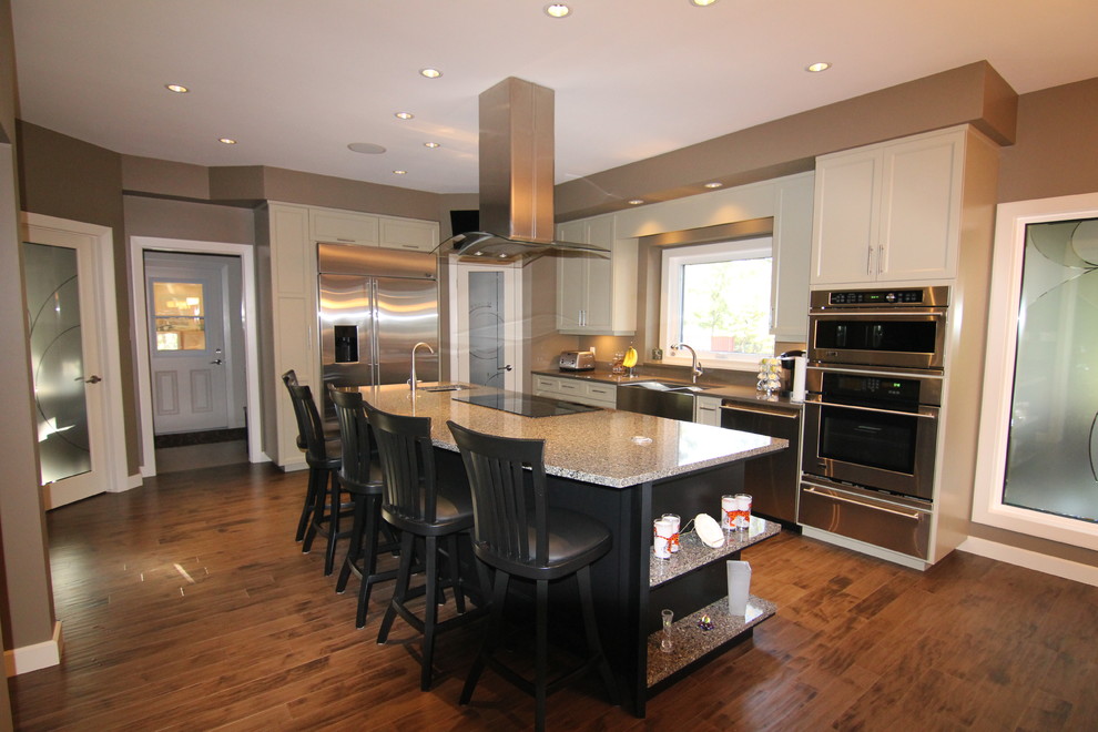 Photo of a mid-sized traditional l-shaped eat-in kitchen in Other with a farmhouse sink, shaker cabinets, white cabinets, quartzite benchtops, stainless steel appliances, medium hardwood floors and with island.