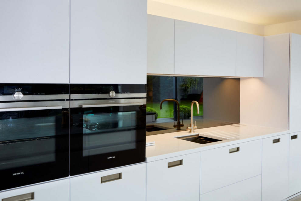 Foto di una cucina design di medie dimensioni con ante lisce, ante bianche, top in granito, paraspruzzi a effetto metallico, paraspruzzi a specchio, elettrodomestici da incasso e top blu