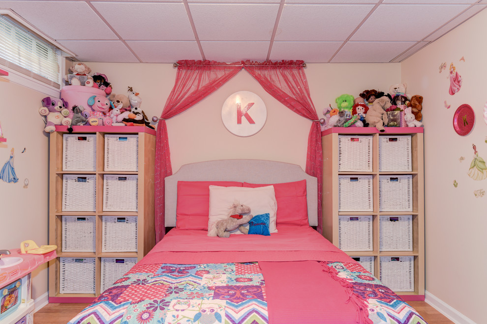 Mid-sized transitional kids' bedroom in Philadelphia with pink walls and light hardwood floors for girls.