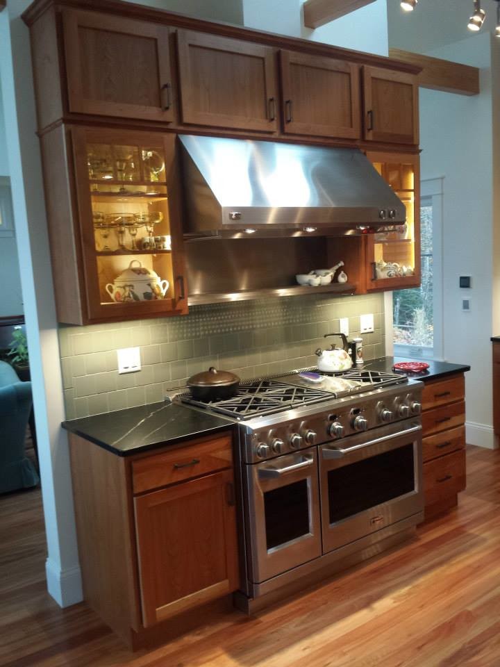 Inspiration for a large transitional medium tone wood floor and brown floor kitchen remodel with shaker cabinets, medium tone wood cabinets, soapstone countertops, stainless steel appliances and black countertops