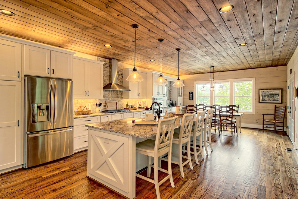 This is an example of a country galley eat-in kitchen in Atlanta with a farmhouse sink, shaker cabinets, white cabinets, stainless steel appliances, medium hardwood floors, with island, brown floor and beige benchtop.