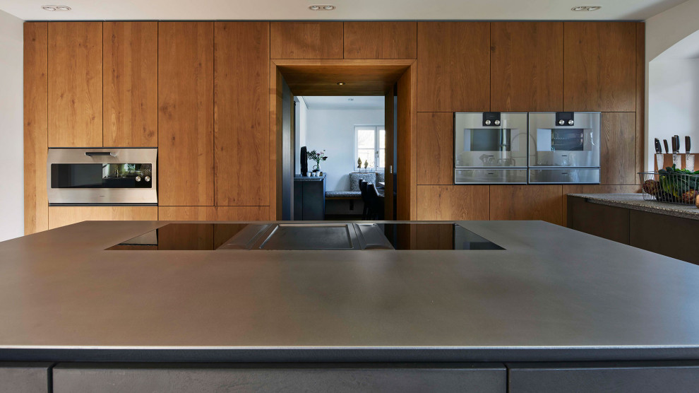 Cette photo montre une cuisine ouverte tendance avec des portes de placard grises, un plan de travail en inox, parquet peint et îlot.