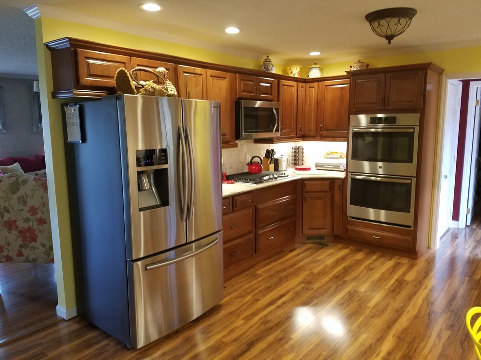 Eat-in kitchen - large u-shaped medium tone wood floor eat-in kitchen idea with an undermount sink, raised-panel cabinets, medium tone wood cabinets, quartzite countertops, beige backsplash, ceramic backsplash, stainless steel appliances and no island