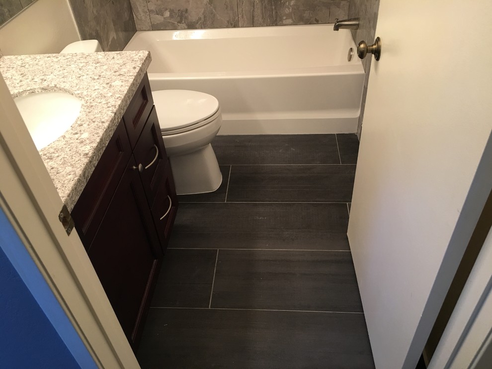 Small contemporary kids bathroom in Los Angeles with shaker cabinets, brown cabinets, a drop-in tub, a shower/bathtub combo, a one-piece toilet, brown tile, porcelain tile, beige walls, porcelain floors, an undermount sink, quartzite benchtops and grey floor.
