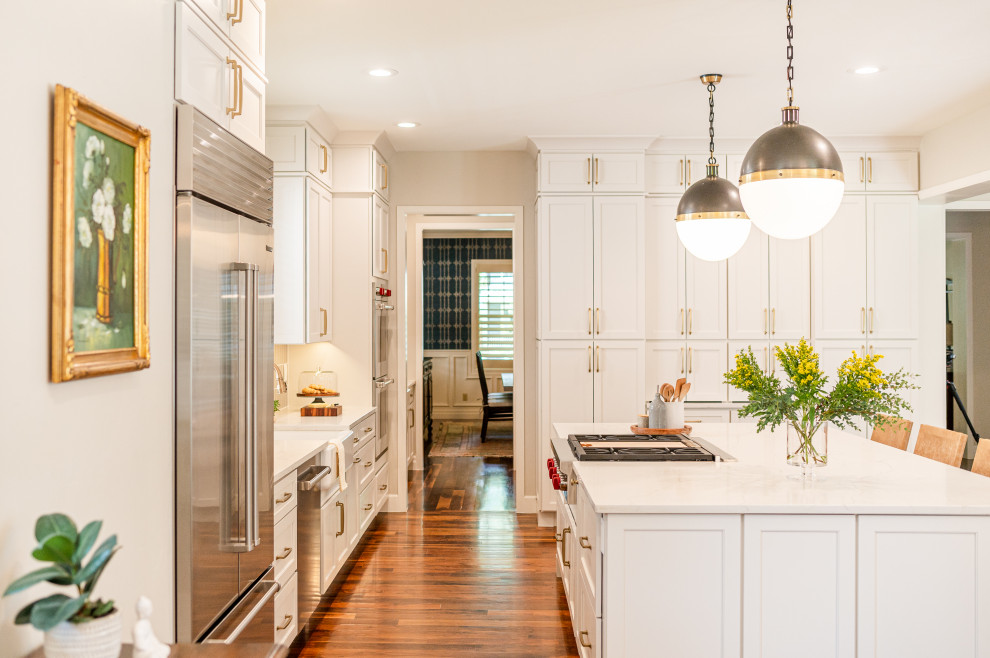 Open concept kitchen - large transitional l-shaped dark wood floor and brown floor open concept kitchen idea in Denver with a farmhouse sink, shaker cabinets, beige cabinets, quartz countertops, beige backsplash, ceramic backsplash, stainless steel appliances, an island and white countertops