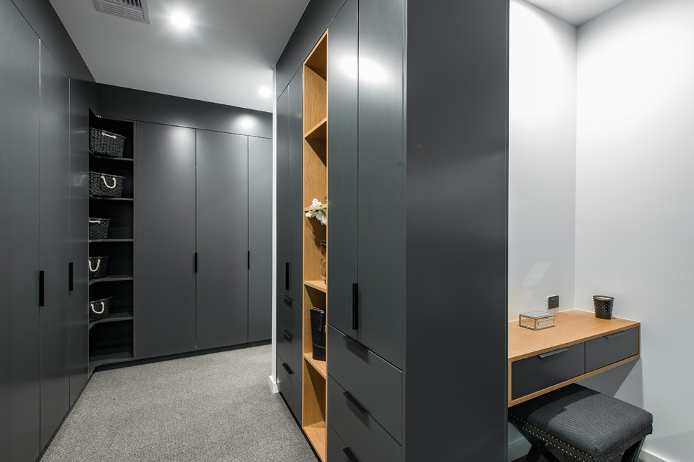 This is an example of a contemporary gender-neutral walk-in wardrobe in Canberra - Queanbeyan with flat-panel cabinets, grey cabinets, carpet and grey floor.