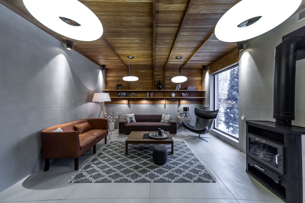 Foto de salón contemporáneo con paredes grises, estufa de leña, marco de chimenea de metal y suelo gris