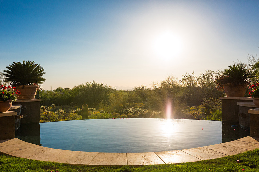 Large traditional backyard custom-shaped infinity pool in Phoenix.