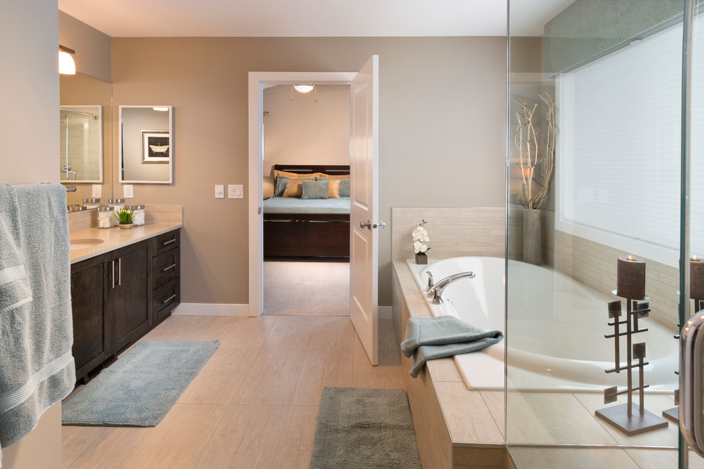 Mid-sized traditional master bathroom in Calgary with an undermount sink, recessed-panel cabinets, dark wood cabinets, granite benchtops, a drop-in tub, a corner shower, beige tile and brown walls.