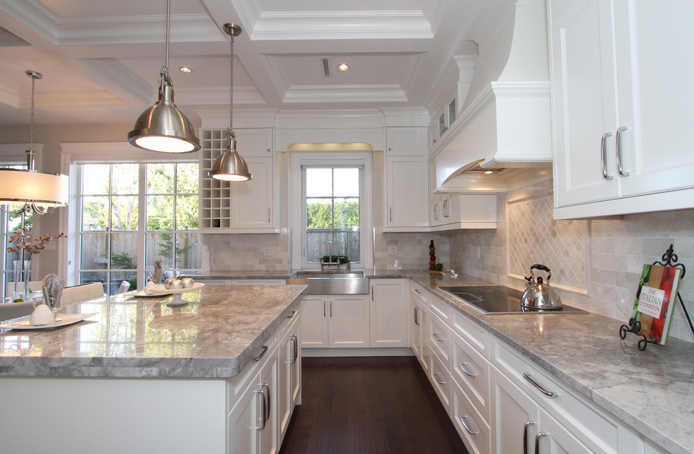 Example of a mid-sized transitional l-shaped dark wood floor eat-in kitchen design in Vancouver with a farmhouse sink, shaker cabinets, white cabinets, gray backsplash, stainless steel appliances, an island, granite countertops and stone tile backsplash