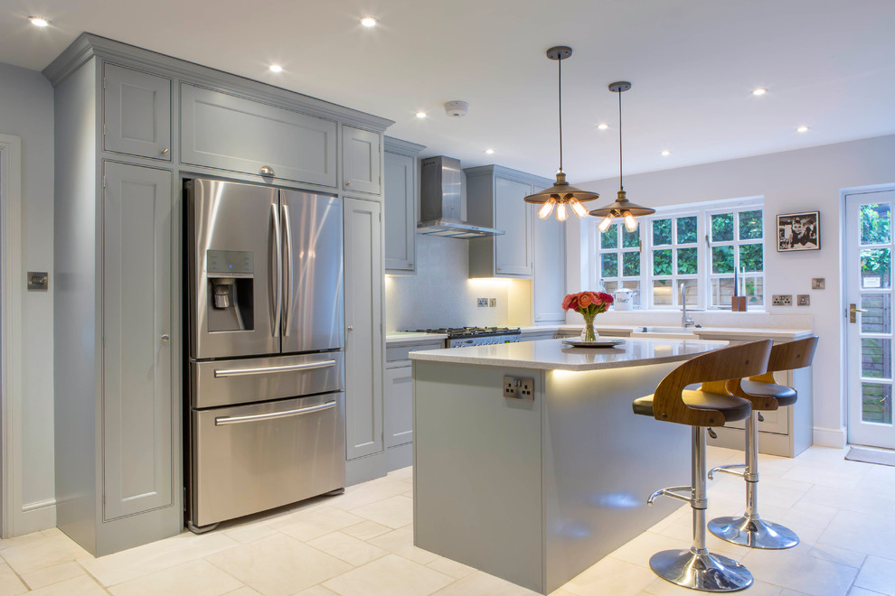 This is an example of a transitional l-shaped open plan kitchen in Buckinghamshire with a farmhouse sink, recessed-panel cabinets, grey cabinets, stainless steel appliances and with island.