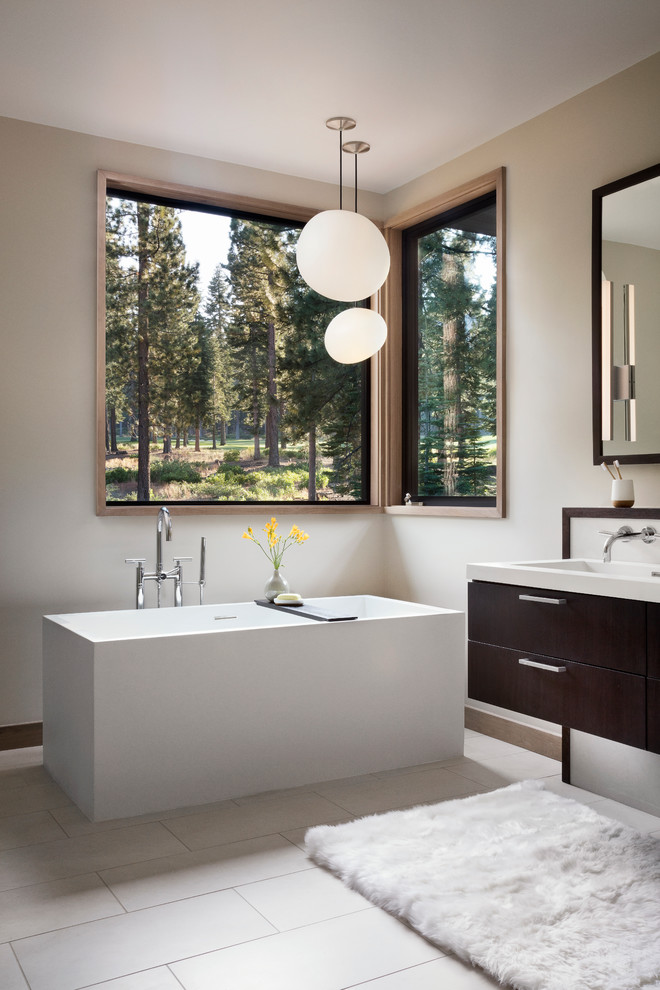 This is an example of a large transitional master bathroom in San Francisco with flat-panel cabinets, dark wood cabinets, a freestanding tub, porcelain floors, a trough sink, a one-piece toilet, blue tile, subway tile, white walls and solid surface benchtops.