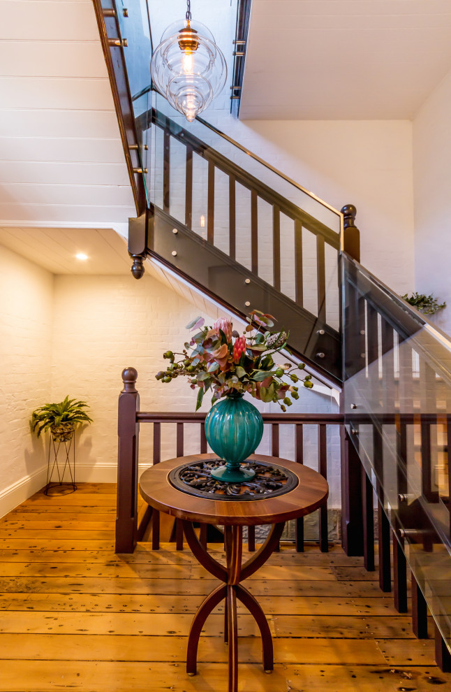 ブリスベンにあるお手頃価格の広いトラディショナルスタイルのおしゃれな直階段 (木の蹴込み板、木材の手すり、レンガ壁) の写真