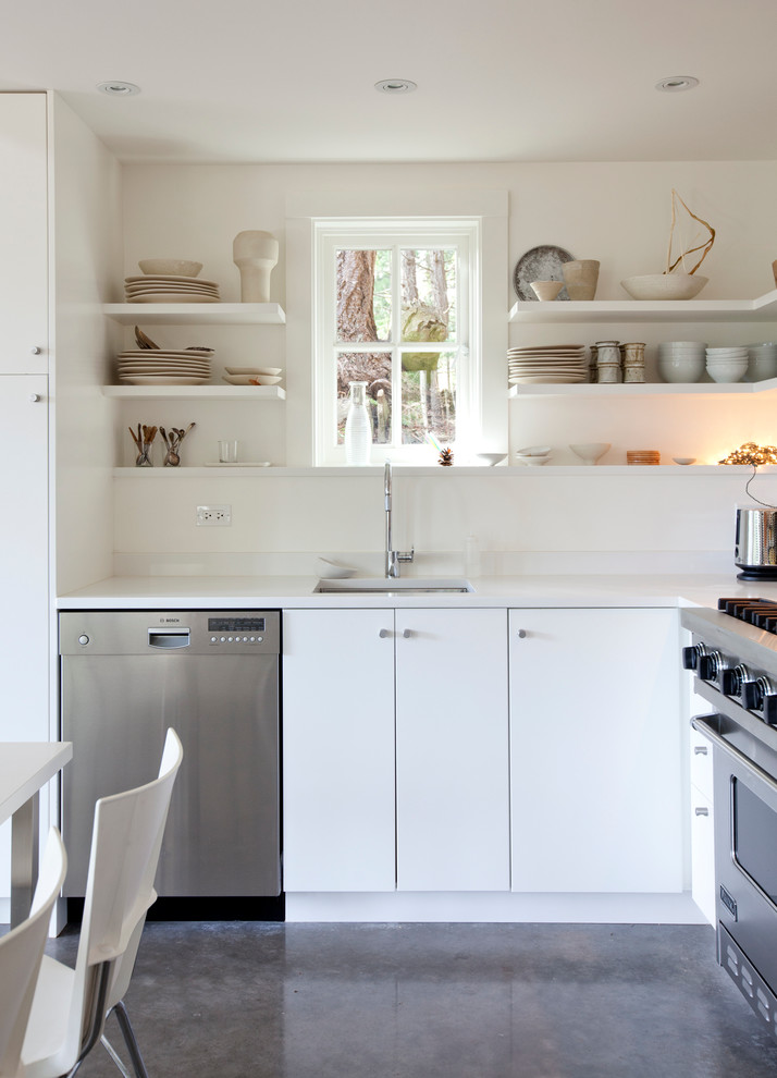 This is an example of a beach style eat-in kitchen in Vancouver with flat-panel cabinets, white cabinets and stainless steel appliances.