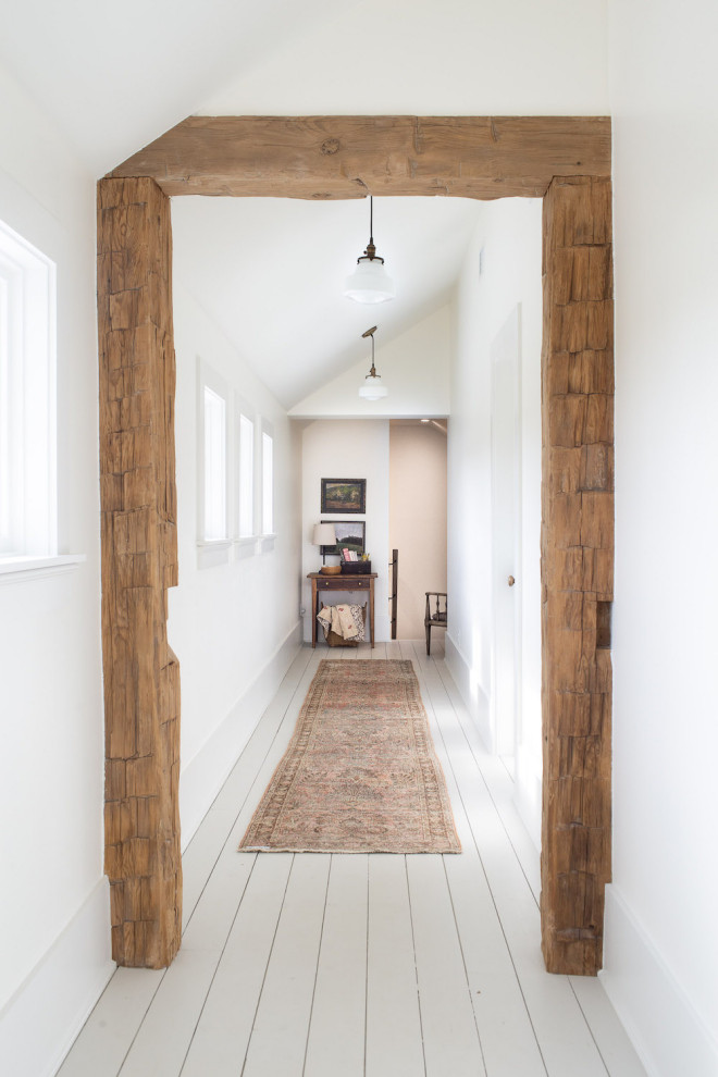 Example of a large cottage light wood floor, brown floor and exposed beam hallway design in Dallas with white walls