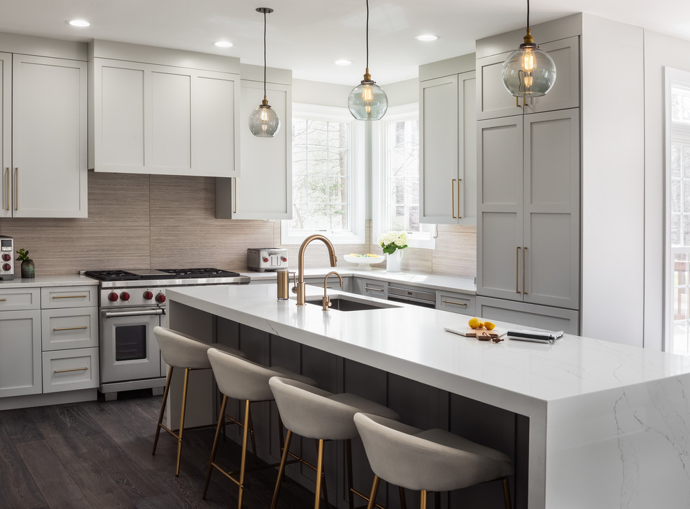 Large transitional l-shaped kitchen in DC Metro with shaker cabinets, grey cabinets, quartz benchtops, white benchtop, an undermount sink, brown splashback, stainless steel appliances, dark hardwood floors and with island.