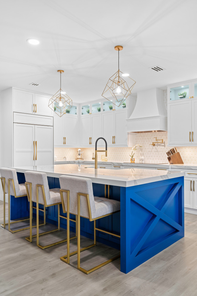 Inspiration for a transitional l-shaped light wood floor and gray floor kitchen remodel in Miami with a farmhouse sink, shaker cabinets, white cabinets, white backsplash, mosaic tile backsplash, paneled appliances, an island and white countertops