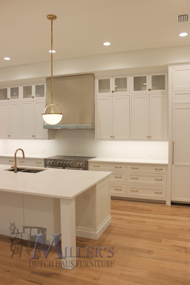 Photo of a large transitional l-shaped open plan kitchen in Tampa with a drop-in sink, shaker cabinets, white cabinets, with island and beige floor.