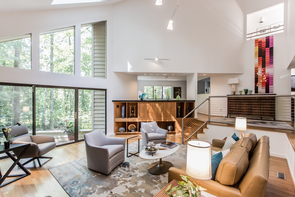 This is an example of a mid-sized midcentury open concept family room in DC Metro with white walls, light hardwood floors, a standard fireplace, a tile fireplace surround, a concealed tv and yellow floor.