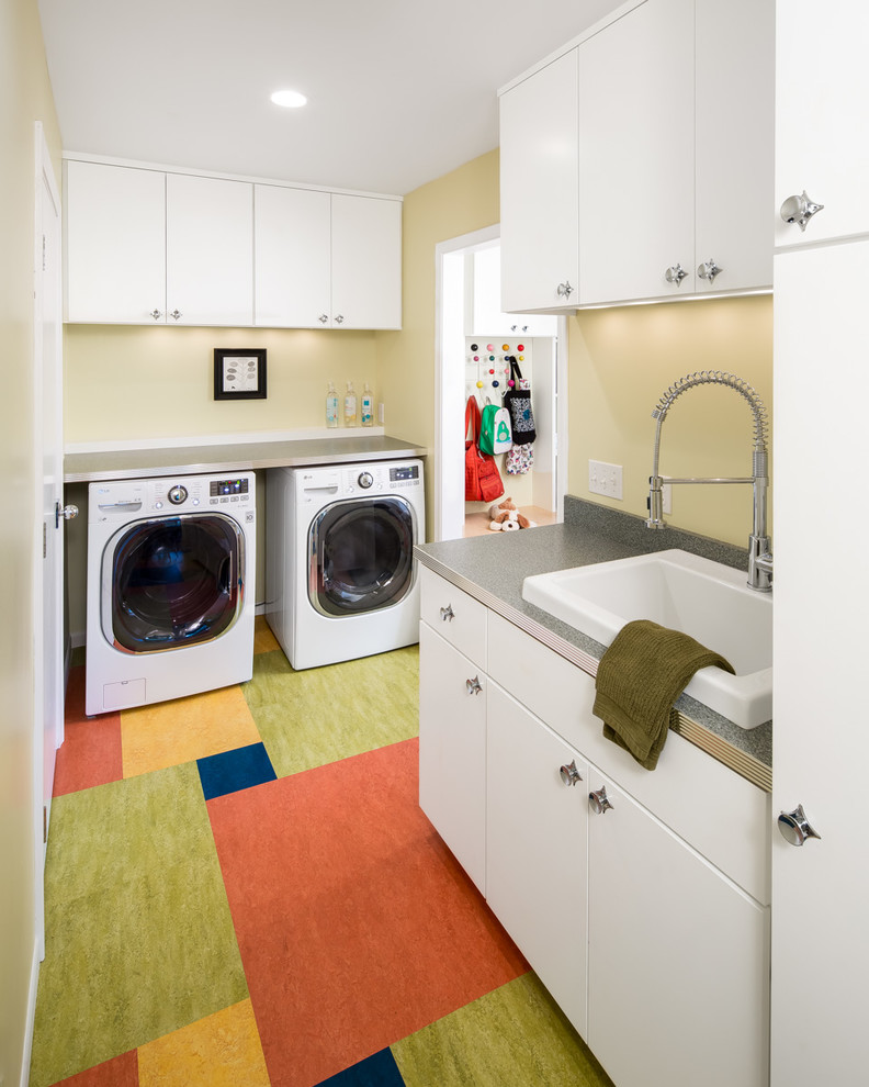 Design ideas for a mid-sized midcentury galley dedicated laundry room in Minneapolis with a drop-in sink, flat-panel cabinets, white cabinets, beige walls and a side-by-side washer and dryer.
