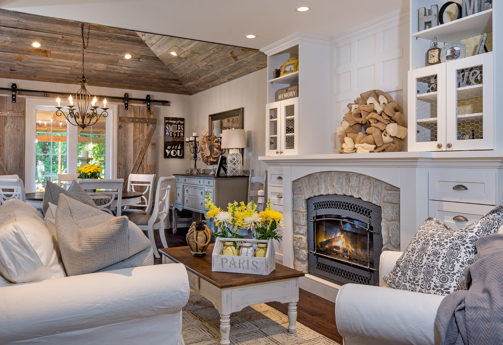 Photo of a country open concept living room in Toronto with medium hardwood floors, a standard fireplace, a stone fireplace surround, no tv and white walls.