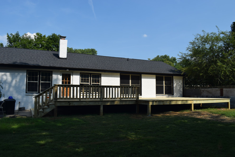 Example of a large backyard ground level wood railing deck design with a roof extension