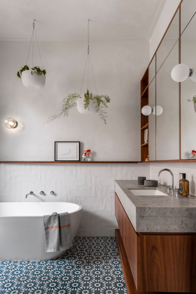 Contemporary bathroom in Other with flat-panel cabinets, medium wood cabinets, a freestanding tub, white tile, white walls, an undermount sink, blue floor, grey benchtops, a single vanity and a floating vanity.