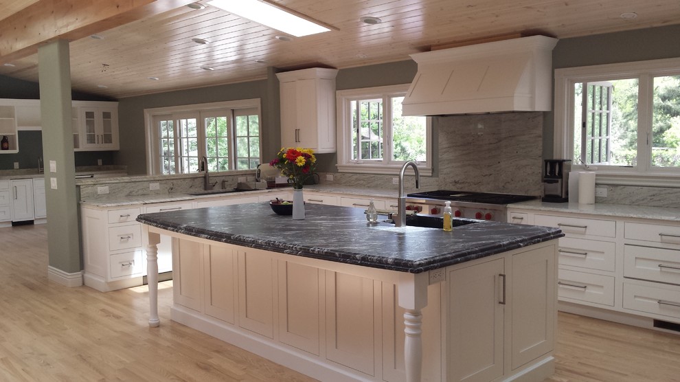 Inspiration for a large rustic u-shaped light wood floor open concept kitchen remodel in Denver with an undermount sink, shaker cabinets, white cabinets, granite countertops, gray backsplash, stone slab backsplash, stainless steel appliances and an island
