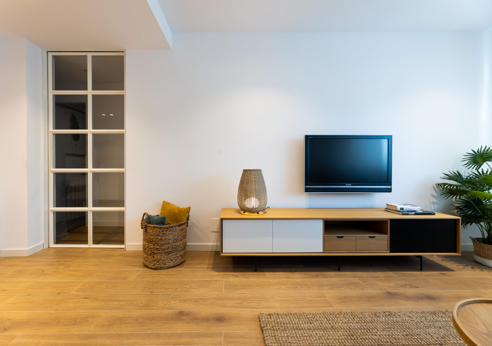 Modelo de salón abierto escandinavo de tamaño medio con paredes blancas, suelo de baldosas de cerámica, televisor colgado en la pared y suelo marrón