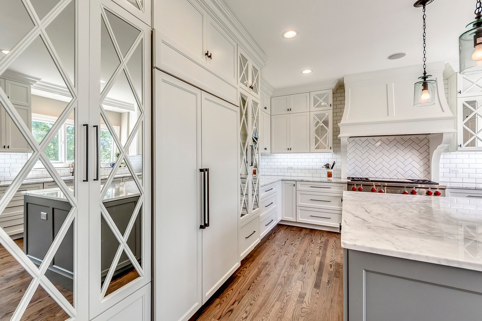 Example of a large transitional dark wood floor and brown floor open concept kitchen design in Chicago with white backsplash, subway tile backsplash, two islands, recessed-panel cabinets, white cabinets, quartzite countertops, paneled appliances and white countertops