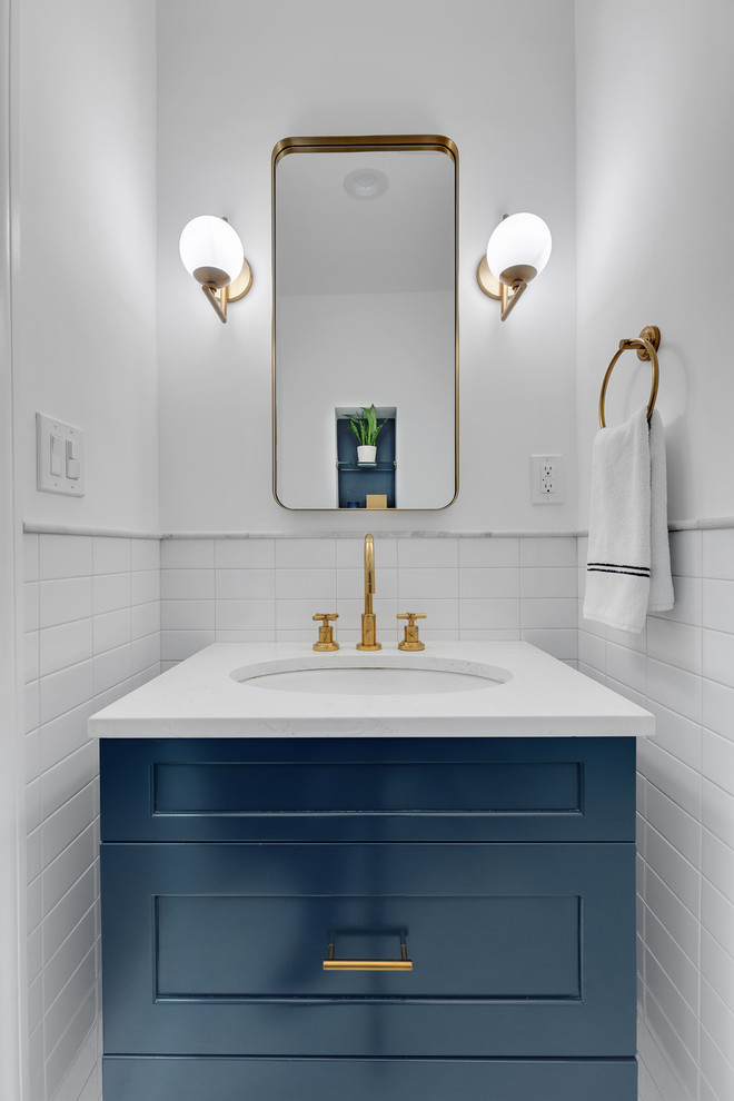 Inspiration for a transitional powder room in New York with shaker cabinets, blue cabinets, white tile, white walls, an undermount sink and white benchtops.
