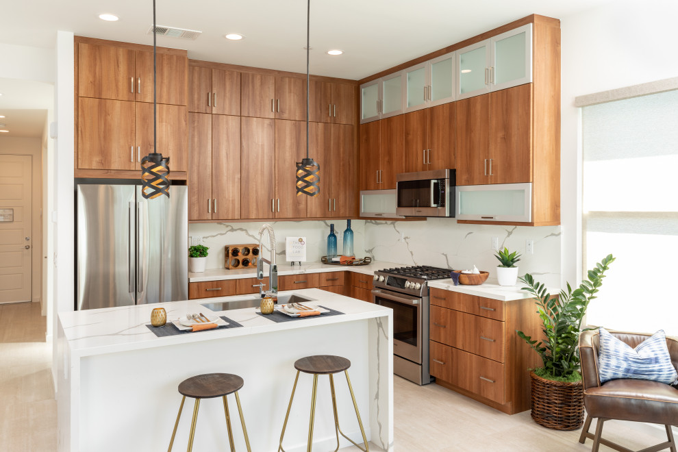 This is an example of a contemporary u-shaped kitchen in Orange County with an undermount sink, flat-panel cabinets, medium wood cabinets, stainless steel appliances, with island, beige floor and multi-coloured benchtop.