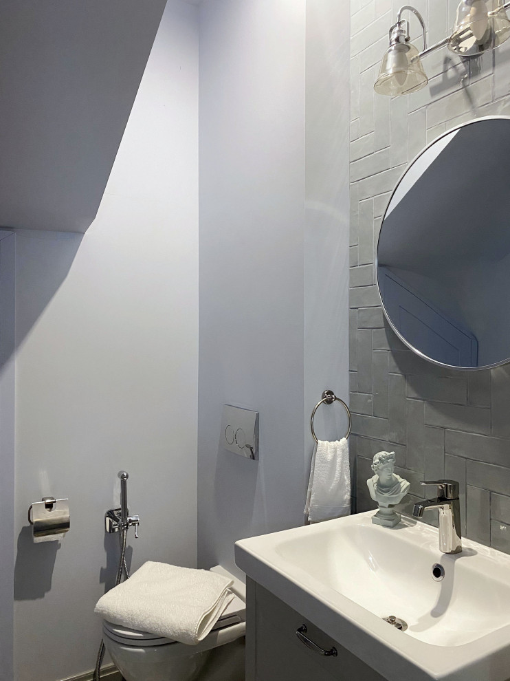 Aménagement d'un WC suspendu classique de taille moyenne avec un placard avec porte à panneau encastré, des portes de placard grises, un carrelage bleu, un carrelage métro, un mur bleu, un sol en carrelage de porcelaine, un lavabo posé, un sol multicolore et meuble-lavabo suspendu.