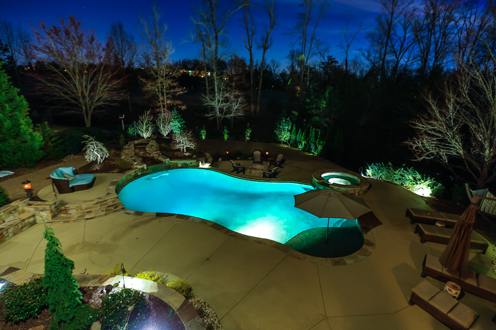 Photo of a mid-sized traditional backyard custom-shaped pool in Atlanta with a hot tub and concrete slab.